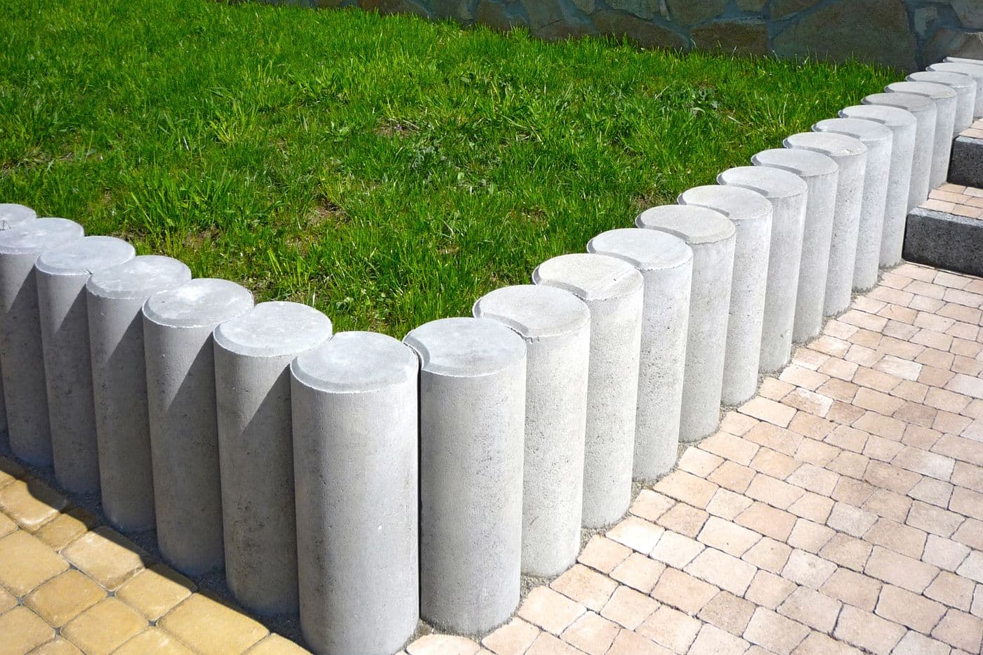 Cast concrete palisade garden edging separating a lawn from a paved path